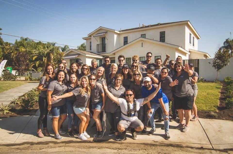The full volunteer build team gathered in front of the completed white two-story home on Extreme Makeover: Home Edition reveal day in Bakersfield